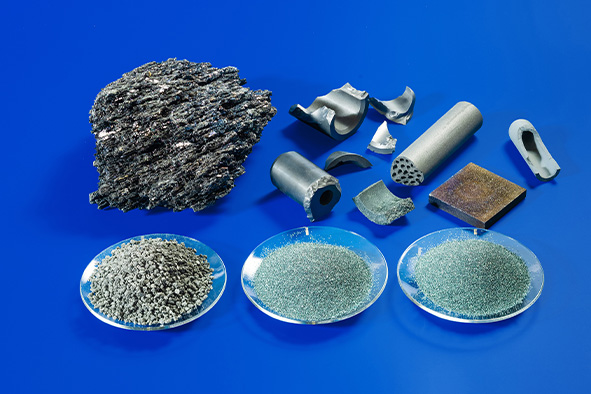 Verschiedene Metall- und Mineralproben in unterschiedlichen Produktionszuständen auf blauer Fläche